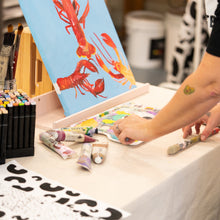Load image into Gallery viewer, Artistic activity with a child painting a colorful lobster on a blue background.
