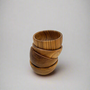 Product photo of small wooden bowls. Four bowls are stacked in a wonky stack