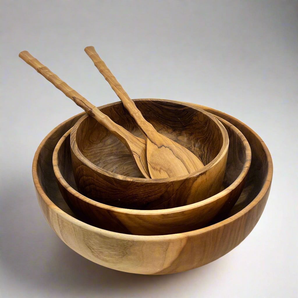 Product photo of wooden salad bowls. Three sizes sitting one inside the other, with wooden salad servers sitting in the middle 