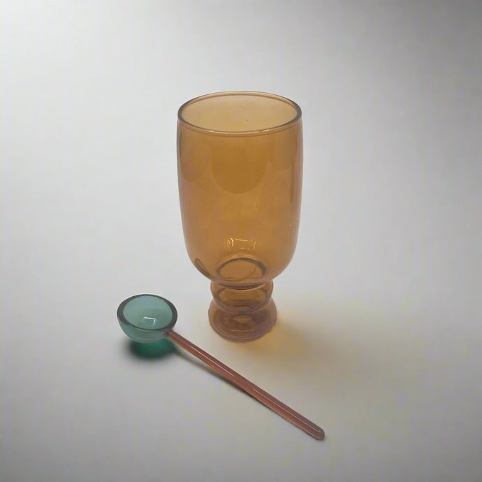 product photo of a tall amber coloured glass with a teal glass spoon