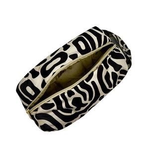 Product photo of a fabric toiletry bag with loop handle. Fabric is a black and beige abstract print. Bag is shown from top with zipper open