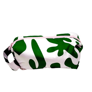 Product photo of a fabric toiletry bag with loop handle. Fabric is a pastel pink with a green abstract pattern