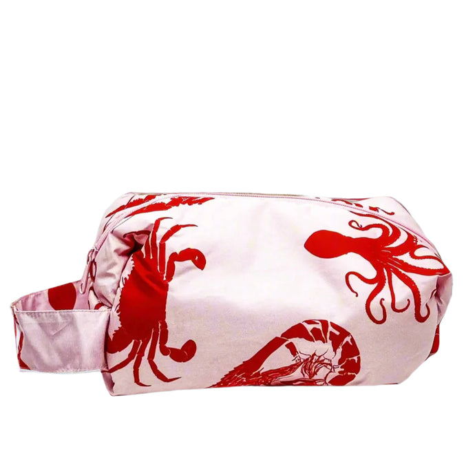 Product photo of a fabric toiletry bag with loop handle. Fabric is a pastel print with a bright red sea creatures print