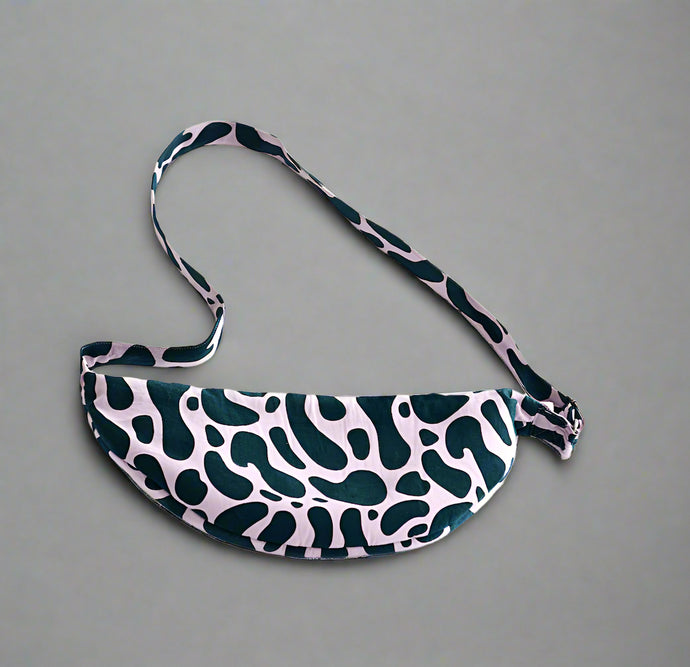 Product photo of a fabric sling bag with long handle. Dark teal and lilac abstract print