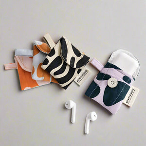 product photo of fabric airpods case. four cases in different abstract, colourful patterns.